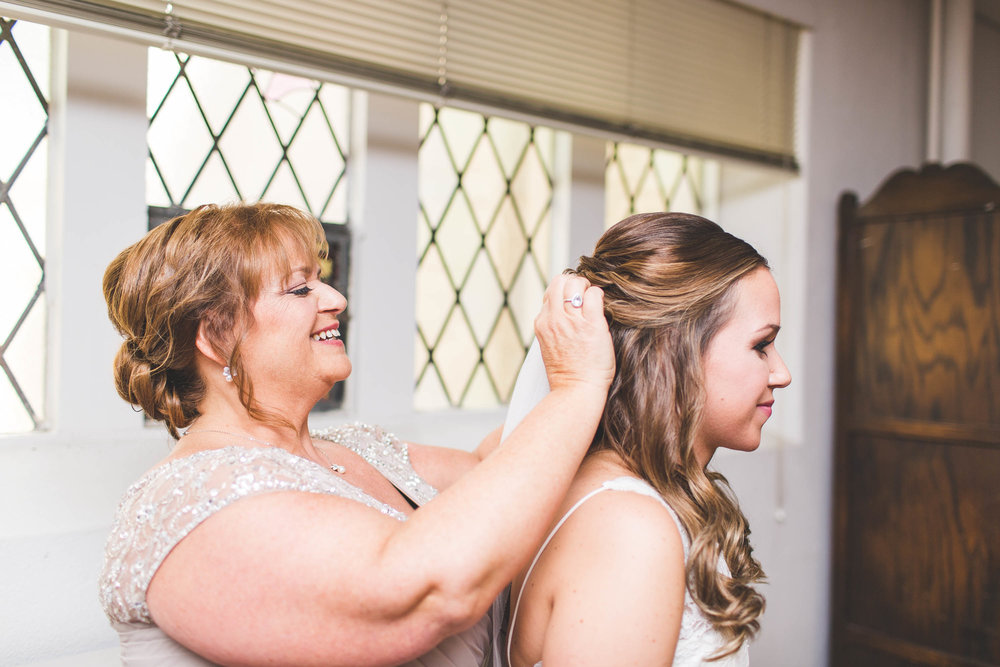 mother of bride putting on bridal veil for wedding