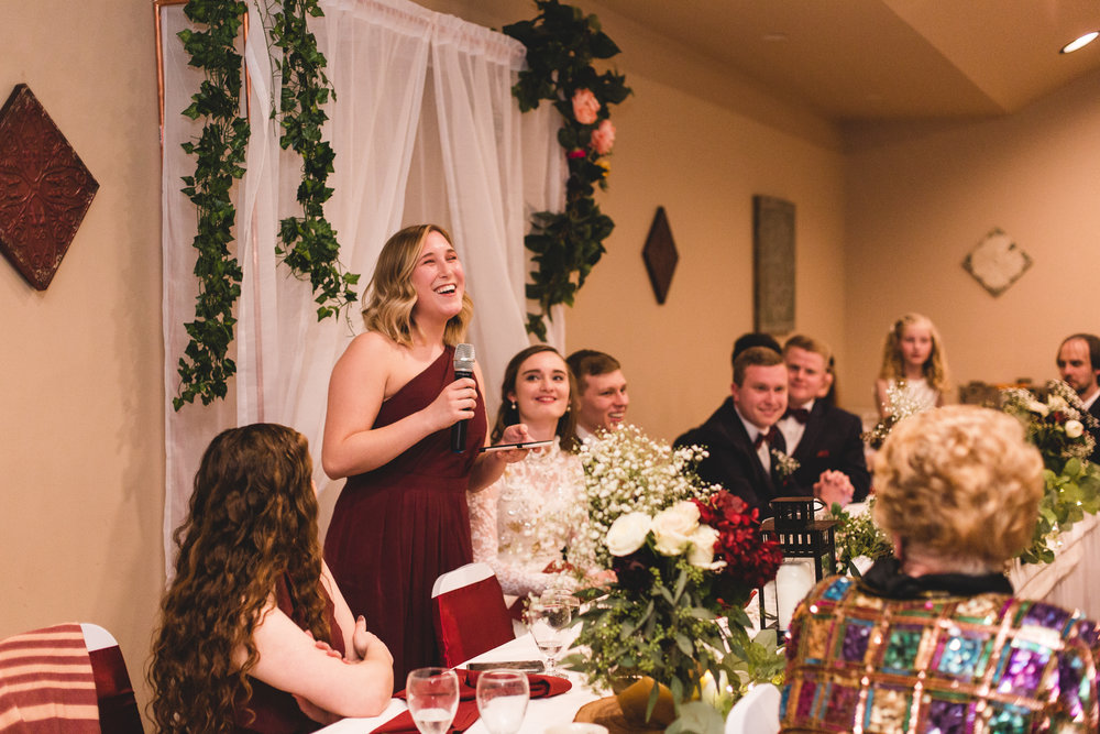 maid of honor giving toast speech laughing at wedding reception