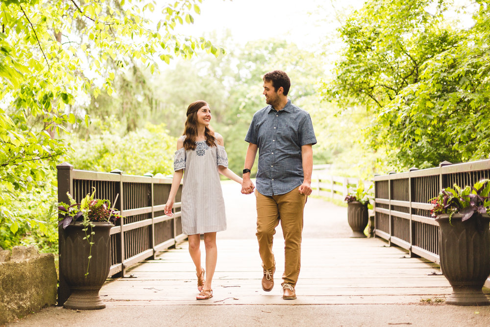 engaged couple walking on bridge at innis woods metro park