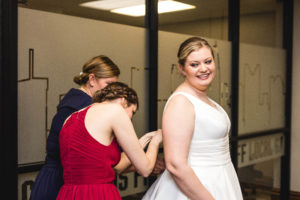 bride smiles at family as they finish putting together her dress at station 67 in columbus ohio