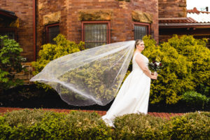 bride looks off in distance as wedding dress veil is blown by the wind in front of historic train station in columbus ohio