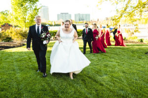 bride laughs as wedding party walk through green grass in columbus ohio