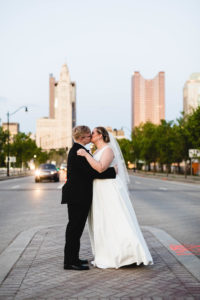 Bride and groom kiss and embrace at sunset on busy urban street in Columbus, Ohio