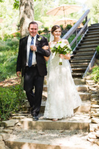 Father and bride walking down stone steps in a forest for a wedding