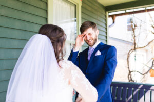 groom cries as he sees a bride during a first look on a green porch
