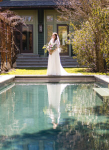 bridal portrait in front of a pool on a sunny day with a green house in the background