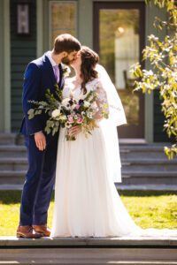 bride and groom kiss on a sunny day in front of a green house in clintonville ohio