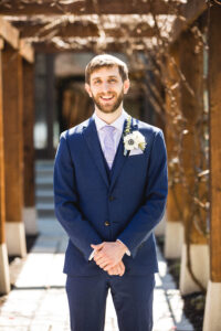 groom portrait on a sunny wedding day under a trellis