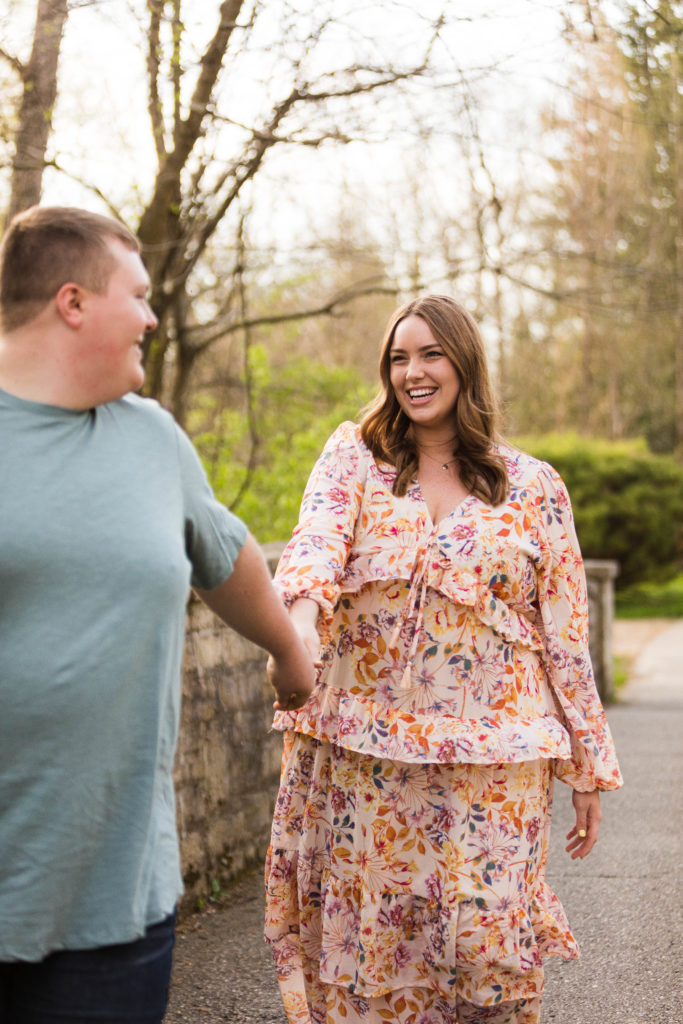 couple walking in a park by a stone wall beautiful smile in a flowery dress