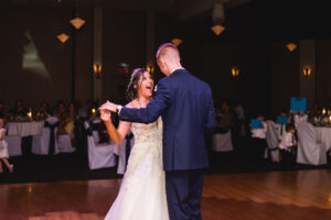A bride and groom share a first dance together and laugh