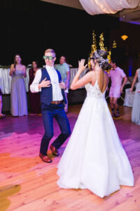 Inside a reception hall the bride and groom dance with LED glasses on