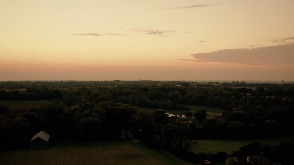 dark landscape beneath red orange and pink sunset sky with a few clouds, birds eye view from a drone at stone valley meadows