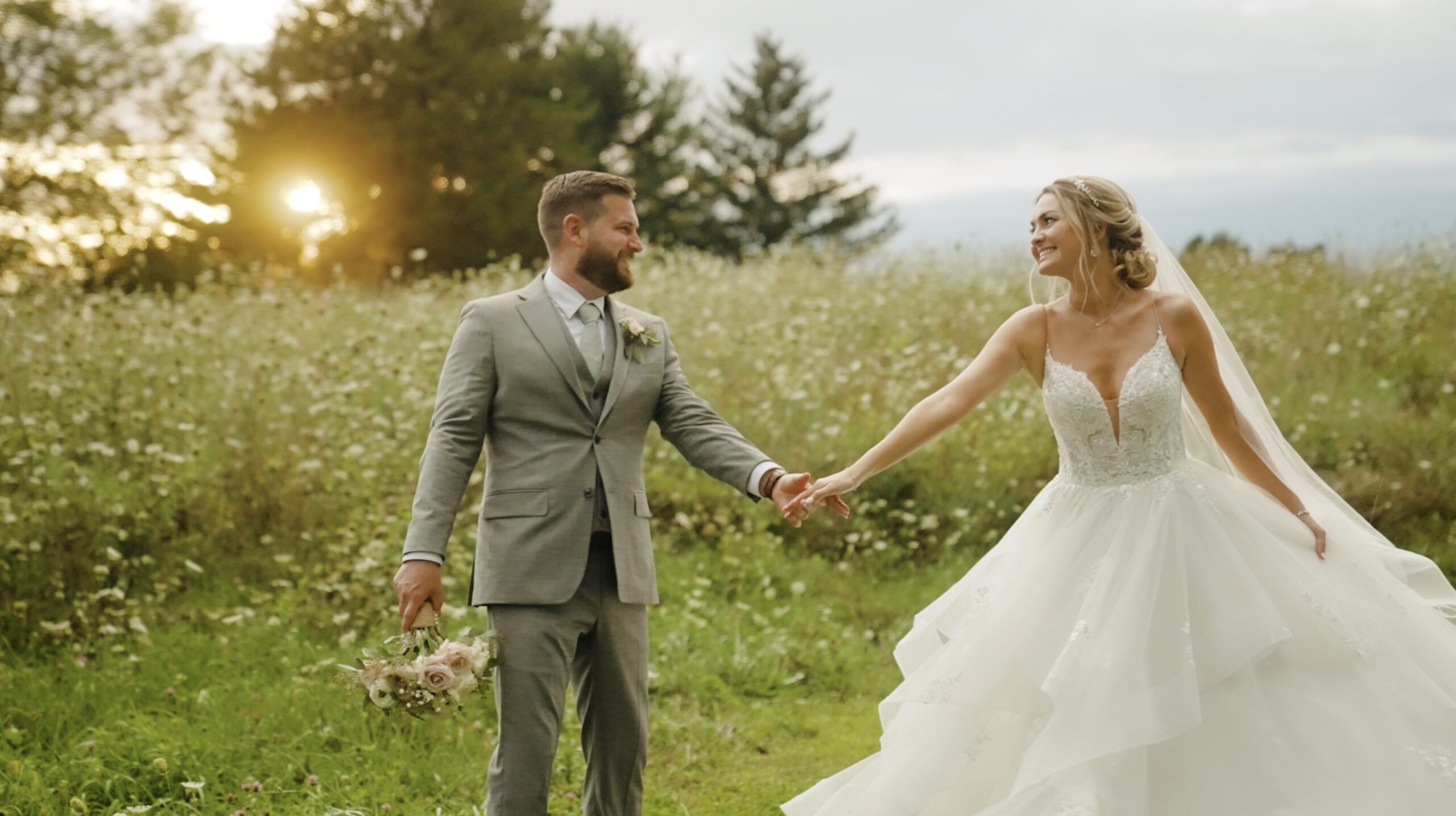 bride and groom walking holding hands in tall grass at sunset, smiling at Ohio Whitetail Lodge