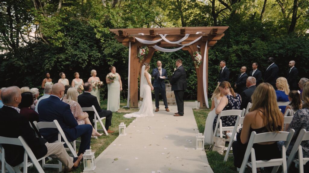 bride and groom getting married in the woods under a wooden arbor at Stone Valley Meadows upscale barn wedding