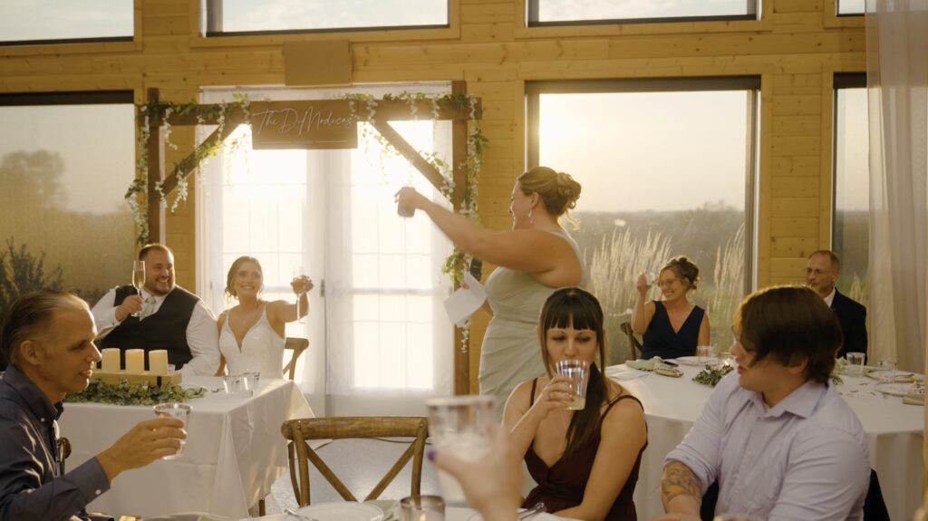 bridesmaid giving a toast on front of sun shining through big windows at stone valley meadows