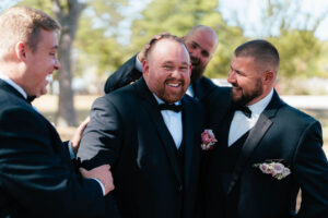 groomsmen playfully goof off with the groom at Flora and Field wedding